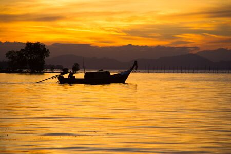 The golden morning light.Fishermen fishing in the early morning golden light.The life of a fisherman. Fishermen on the sea. Photo Fisherman Silhouette.Fisherman boat.の写真素材