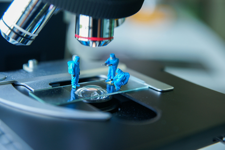 Miniature people scientist At Work on light microscope.の写真素材