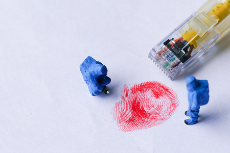 The concept of miniature crime scene investigator with red fingerprint and wired network cableの写真素材