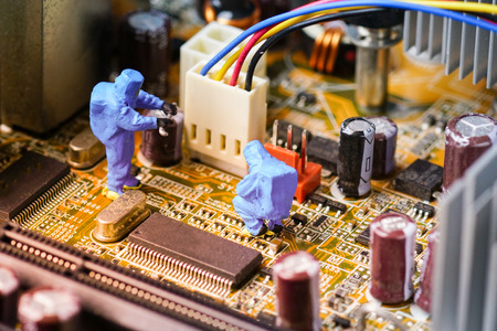 Technicians repair on computer mainboard. Miniature people.