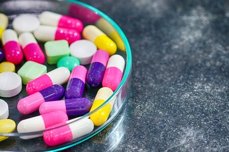 Colorful medicine pills in petri dish on table