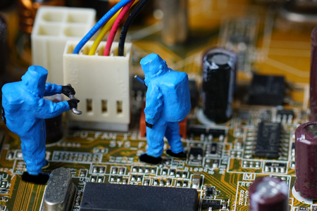 Technicians repair on computer mainboard. Miniature people.
