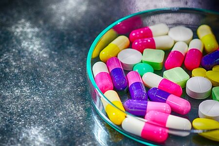 Colorful medicine pills in petri dish on tableの写真素材