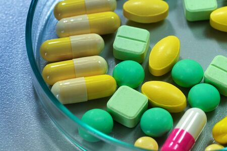 Pharmaceutical medicine pills in petri dish on tableの写真素材