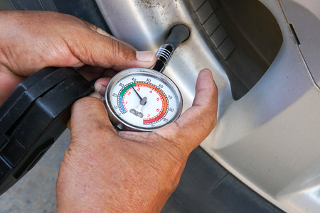 Hand holding pressure gauge for car tire pressure measurement. Vehicle safe concept.の写真素材