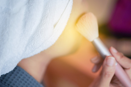 Pretty girl is applying blush on cheek by brush. Beauty Makeup.の写真素材