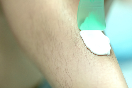 Woman epilating leg with depilation cream and spatula. Scrubs hair removal creamの写真素材