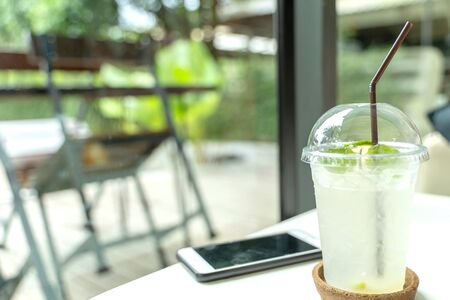 Cool lemon juice in the plastic glass on the white table.の写真素材