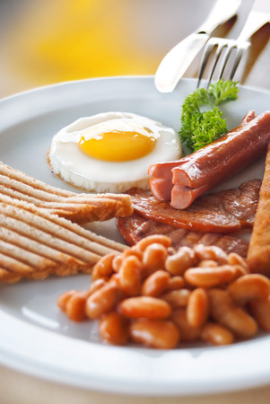 English Breakfast - sunny-side-up fried eggs, sausages, beans, bacon and toasts served with coffeeの写真素材