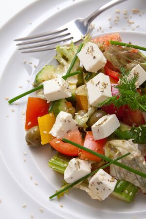 Mediterranean-style Salad with feta cheese, organic green olives, cherry tomatoes, cucumber, fresh basil and parsley. Greek salad. Healthy snack. Concept for a tasty and healthy meal.の写真素材