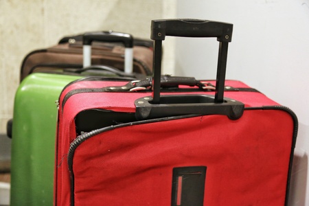 Red broken traveling luggage, crack and torn at the corner with other baggage in background, at the...