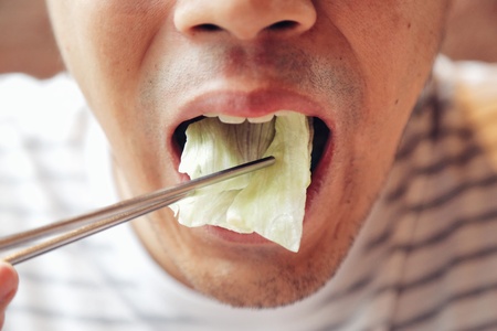 Closeup Asian male eating fresh vegetable food,Napa cabbage, in Chinese style with chopstick. Show concept and idea of healthy.の写真素材