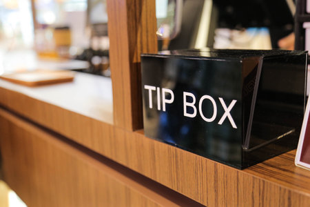 tip box  and few coins inside on wood counterの写真素材