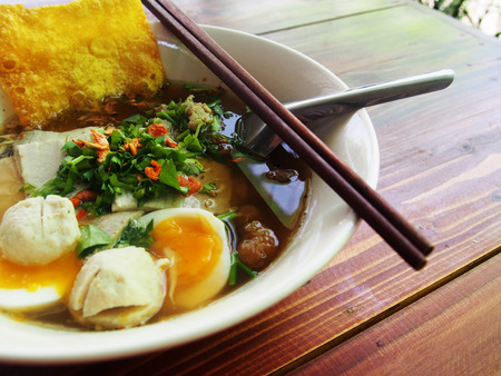 a bowl of noodle soup with egg and crispy wonton
