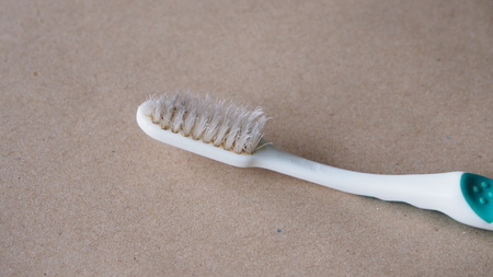 close up of old used toothbrush on brown paper
