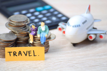 Miniature people love couple sit on coins with plane for tour around world,Concept for those who succeed from saving and investing.の写真素材