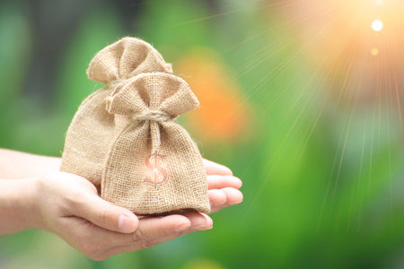 Female hand holding a sacks of money for trading ideas. Or financial investment.の写真素材