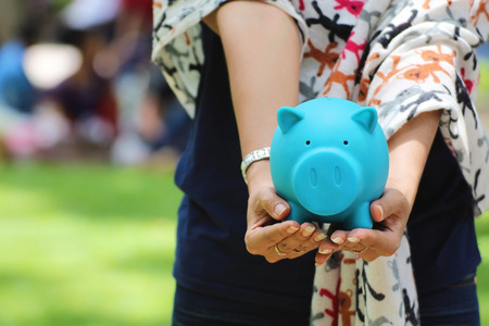 Female hand holding a blue piggy bank, ideas of financial investment or Bankingの写真素材
