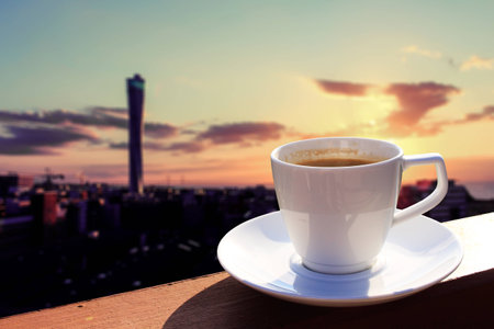 Morning cup of coffee with cityscape background at sunriseの写真素材