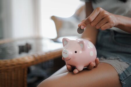 Woman hand putting coin into pink piggy bank, Finance or Savings concept.の写真素材