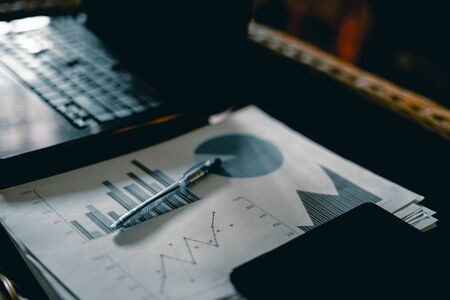 Office desk workspace with laptop, Graph document and pen and smart phone on table.の写真素材