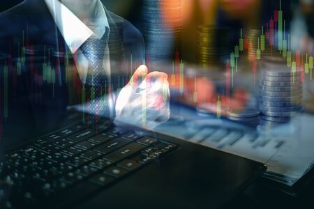 Double exposure businessman with laptop computer and candlestick chart and coins background, financial investment concept.の写真素材