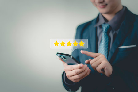 Businessman hand using smart phone and give five star symbol to increase rating of the product and service concept, Customer service experience and business satisfaction surveyの写真素材