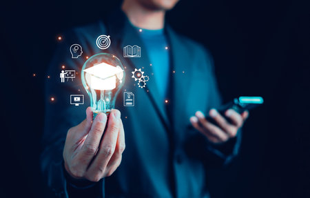 Man hand showing graduation hat icon in light bulb, Diploma, business, book, Study knowledge, Internet education course degree, student, teacher, E-learning graduate certificate program concept.の写真素材