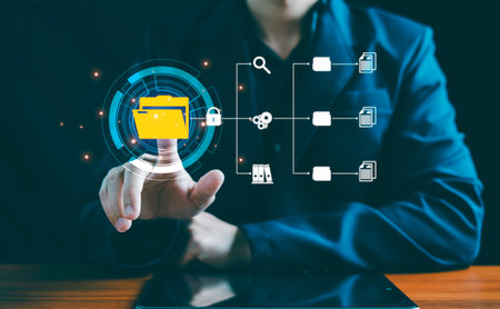 DMS (Document Management System) concept: A businessman points to a folder icon, demonstrating the use of digital software for managing electronic documents in a professional, paperless smart office using cloud services.の写真素材