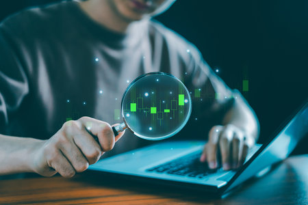 A businessman or trader holds a magnifying glass over a virtual stock market chart, analyzing technical graphs, candlesticks, and indicatorsârepresenting business investment and income earning strategies.の写真素材