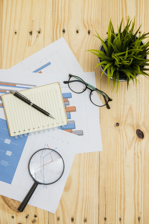 Office workplace with Magnifying glass on wood table,supplies and reports for analysis business planの写真素材