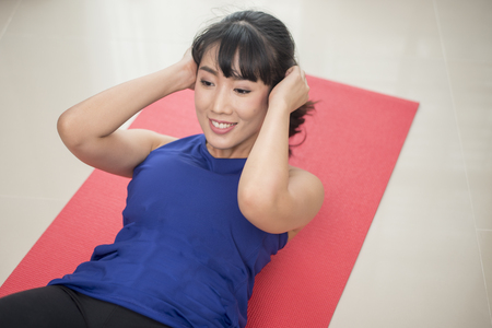 Beautiful Young sporty woman doing  sit-up at homeの写真素材