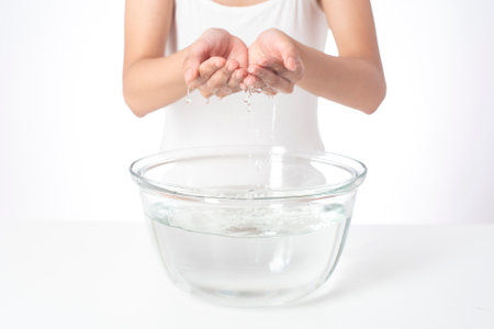 Beautiful woman is washing her face on white backgroundの写真素材