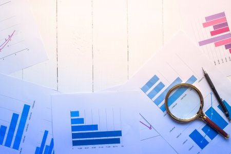 Magnifying glass and documents with analytics data lying on table,selective focus