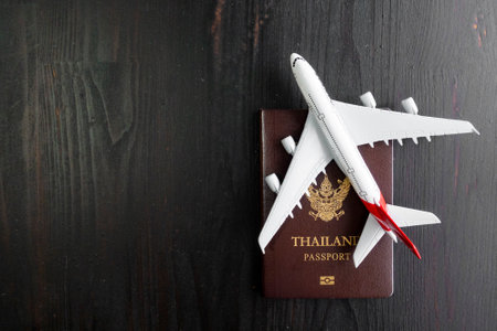 Airplane model and passport on wooden desk, ready travel conceptの写真素材