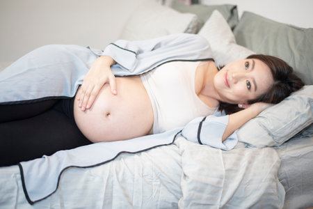 Beautiful asian pregnant woman is sleeping on bedの写真素材