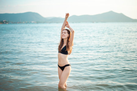 Beautiful woman in black bikini is enjoying with sea water on the beachの写真素材