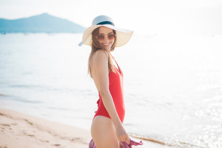 Beautiful woman in red swimsuit is walking on  the beachの写真素材