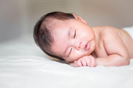 cute newborn baby is sleeping on white bedの写真素材