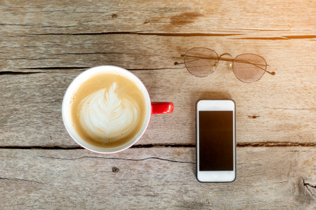hot latte art with smart phone on wood backgroundの写真素材