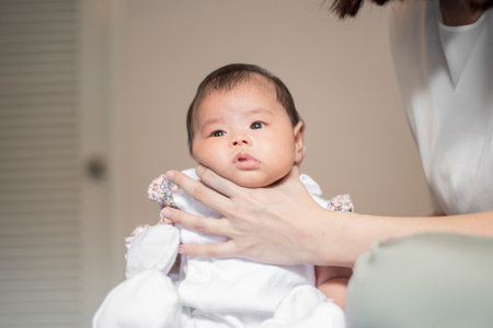 Newborn baby girl is touched her back by mom after drink milk