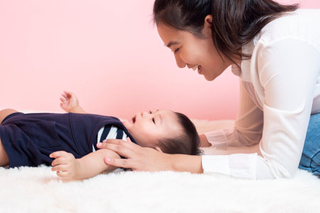 Happy newborn cute baby and beautiful mom in studioの写真素材