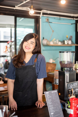 Beautiful barista is smiling  in her coffee shop .の写真素材