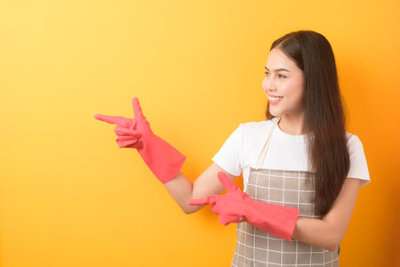 Beautiful woman housekeeper portrait on yellow backgroundの写真素材