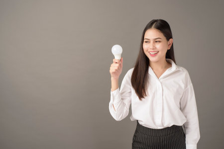 Beautiful intelligent woman is holding light bulb in studio