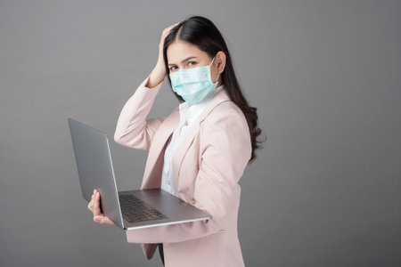 business woman with surgical mask is holding laptop computer