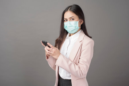 Business woman with surgical mask is using cell phoneの写真素材