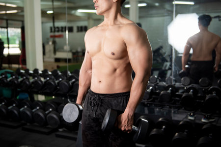 Muscular fitness man bodybuilder is workout with dumbbells in gymの写真素材