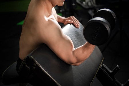 Muscular fitness man bodybuilder is workout with dumbbells in gymの写真素材