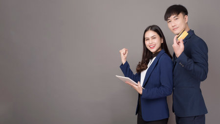portrait of young Asian business people  holding credit card on gray studio backgroundの写真素材